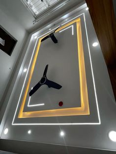 a clock that is on the side of a wall in a room with lights around it