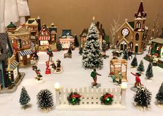 a christmas village is shown with people and trees