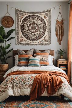 a bed with pillows and blankets on top of it in front of a tapestry wall hanging