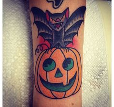 a bat and pumpkin tattoo on the arm