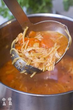 a ladle full of chicken noodle soup being stirred with a wooden spoon