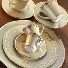 three cups and saucers with gold designs on them