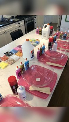 the kitchen counter is covered with pink plates and utensils, including paintbrushes