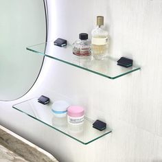 two glass shelves with various items on them in front of a mirror and wall behind it