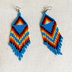 two pairs of beaded earrings with blue and red beads on them, one is hanging from