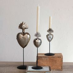 three metal heart shaped candle holders sitting on top of a wooden table