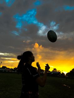 a woman standing on top of a lush green field next to a ball in the sky