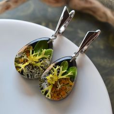 two earrings with flowers on them sitting on a plate