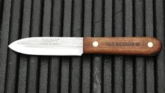 a knife sitting on top of a grill with a wooden handle next to it's blade