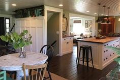 an open kitchen and dining room with wood flooring, white cabinets and counter tops