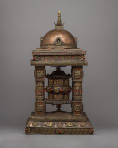 an ornately decorated wooden stand with a bell on it's top and two bells at the base