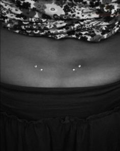 a woman's stomach with three small white dots on the bottom of her belly