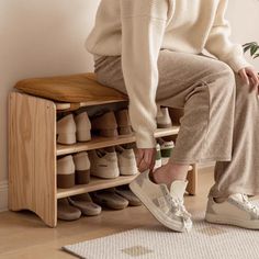 a woman is sitting on a wooden shoe rack