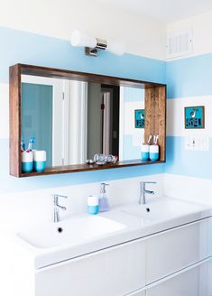 a bathroom with two sinks and mirrors on the wall next to each other in different colors