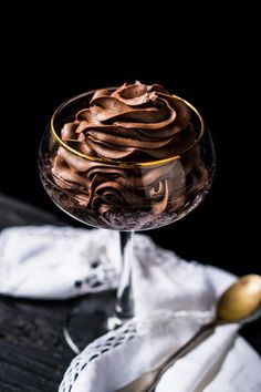 a glass bowl filled with chocolate frosting on top of a wooden table