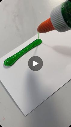 a green marker is being used to paint a white piece of paper with an orange tip