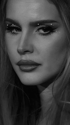 a woman with long hair and dark makeup looks at the camera while wearing black eyeliners