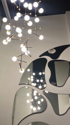 an artistic light fixture hanging from the ceiling in a room with mirrors and lights on it