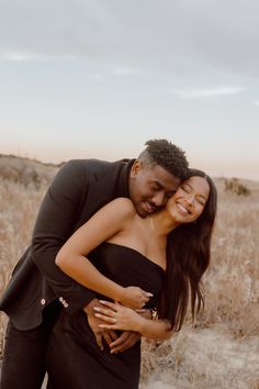 a man and woman hugging in the middle of a field