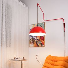 a red lamp hanging from the side of a white wall next to a yellow chair