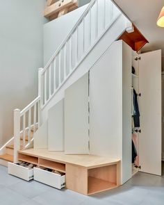 an open closet under the stairs in a house with white walls and wooden steps leading up to it's second floor