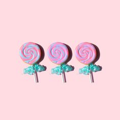 three candy lollipops sitting on top of each other in front of a pink background