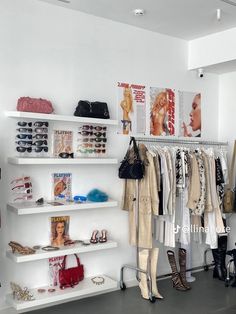 a woman's clothing store with white shelves and shoes on the floor, purses hanging from them