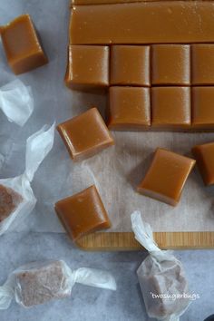 several pieces of chocolate sitting on top of a cutting board next to plastic wrappers