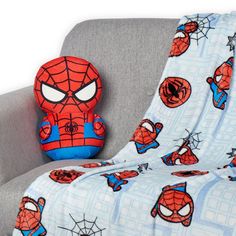 a spiderman pillow sitting on top of a gray couch next to a stuffed animal