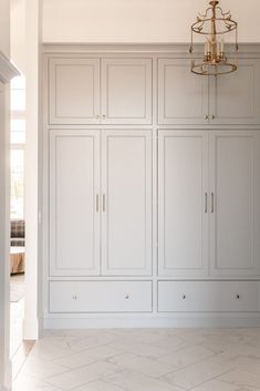 an empty room with white cabinets and chandelier