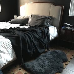 an unmade bed in a bedroom with black walls