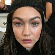 a close up of a person with long hair and blue eyes wearing a black hat