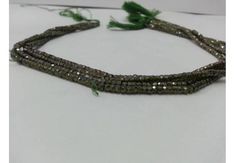 three strands of beads with green leaves on the bottom and one strand has silver colored beads