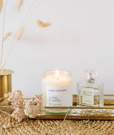 a white candle sitting on top of a table next to a gold tray with flowers