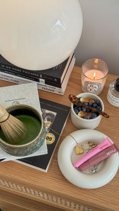 a wooden table topped with bowls filled with green liquid and other items next to a lamp