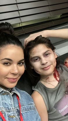 two girls with makeup and blood on their faces are posing for the camera while one girl has her face painted red