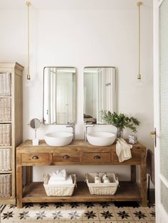 two bathroom sinks with mirrors above them and baskets under the sink on top of it