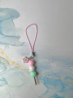 a keychain with a flower and two beads attached to it on a white surface