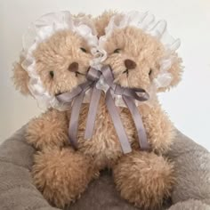 two teddy bears with white ruffles and bows on their heads are sitting next to each other