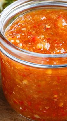 a glass jar filled with sauce sitting on top of a wooden table