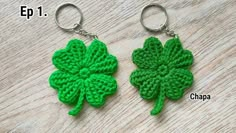 two green crocheted shamrocks sitting on top of a wooden table next to each other