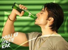 a man drinking from a green bottle while standing in front of a green and white background