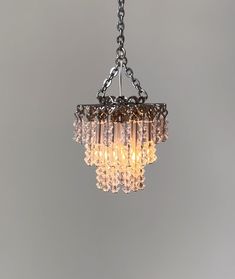 a chandelier hanging from a chain on a gray wall