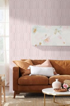 a living room with pink wallpaper and brown couch in the corner, coffee table on rug