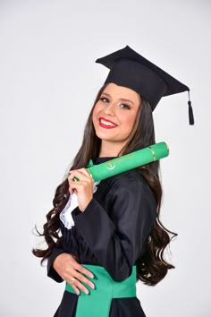 a woman in a graduation gown holding a green graduate's cap and tassel