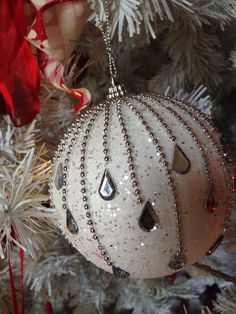 a white ornament hanging from a christmas tree decorated with red and silver ornaments