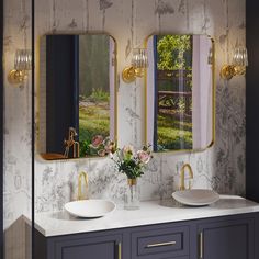 a bathroom with two sinks and mirrors on the wall next to it is decorated in gold