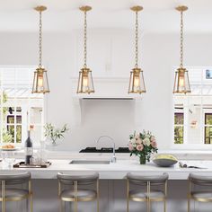 a kitchen with white counter tops and gold pendant lights