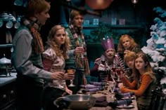 a group of people sitting around a table in front of christmas trees with candles on them