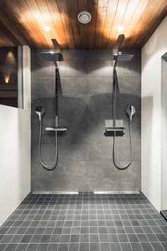 two shower heads mounted to the side of a wall next to a tiled floor in a bathroom